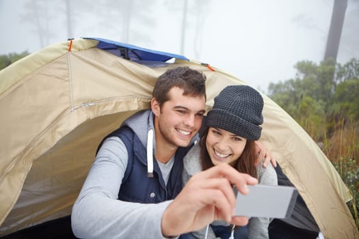 Camping selfies. a young couple taking a photo of themselves while on a camping trip.