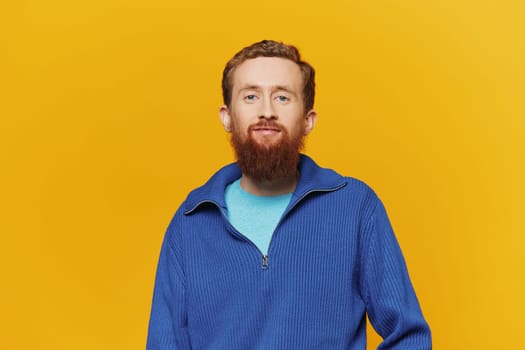 Portrait of a man smiling in a blue sweater on a yellow background copy space, space for text