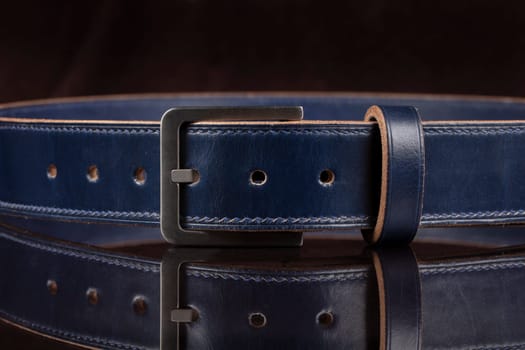 Part of a blue leather belt on a black background.