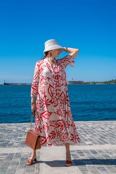 woman in a hat and dress enjoys the blue sea and summer. Welcome summer.