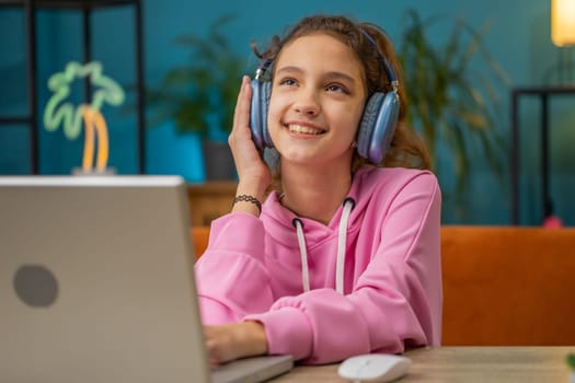 Preteen school girl in headphones listens to music or lesson, distance online learning relaxing