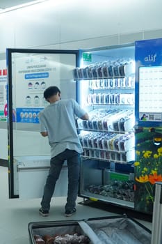 Jakarta, Indonesia. April 20, 2023. A young man is refilling the items on the vending machine at MRT Station. Public service photography.