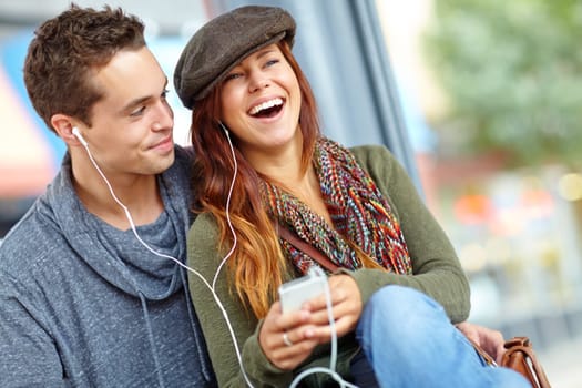 I love her so much. A pretty girl sharing her earphones with her boyfriend as they listen to music from her phone.
