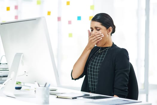 I could use a nap right now. a young businesswoman yawning while working in an office.