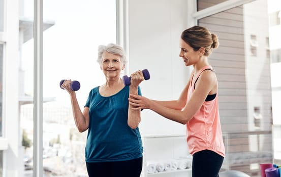 Giving her client a boost of motivation. a fitness instructor helping a senior woman with some weightlifting exercises.