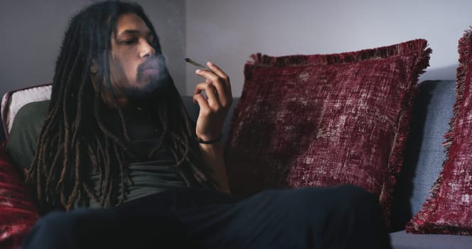 Getting high at home. a young man smoking a marijuana joint at home.