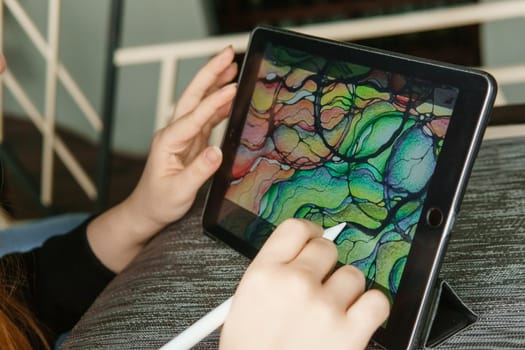 TVER, RUSSIA - FEBRUARY 11, 2023: A young woman draws neurography with a stylus on a tablet. Psychological session to remove restrictions, art therapy