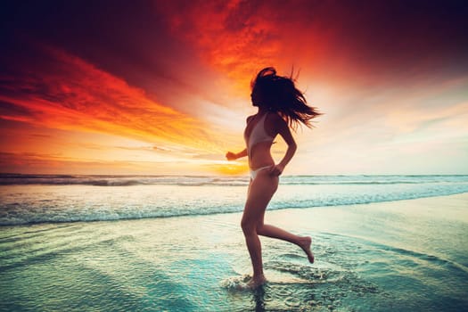 Woman running on the beach at sunset