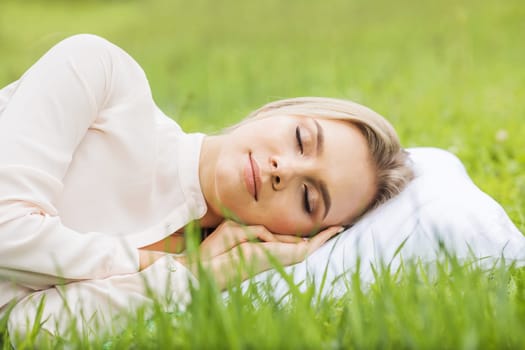 Woman sleeping on pillow in grass