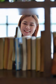 Portrait of a young Asian woman showing joy as she searches for knowledge in the library