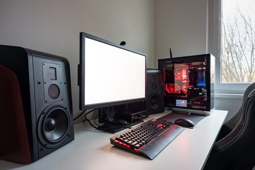 Custom built gaming computer with white screen, keyboard, mouse, desktop, components, hardware, gaming chair. Modern desktop gaming setup on desk. Modern gaming concept and white computer display