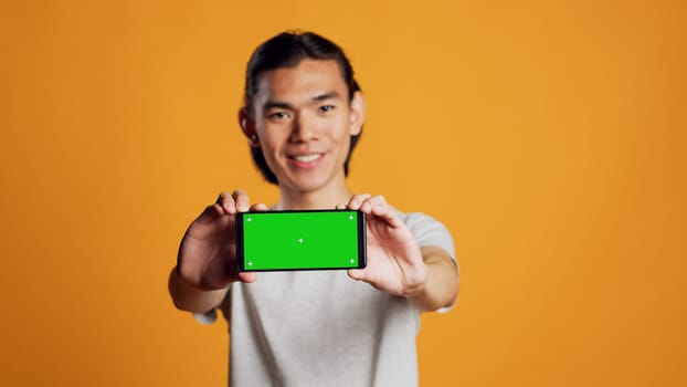Male model holding horizontal greenscreen mobile phone