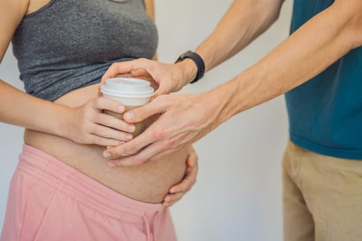 Husband forbids pregnant wife to drink coffee. A pregnant woman holds a cup of coffee in her hands. Caffeine safety, myths about coffee during pregnancy concept