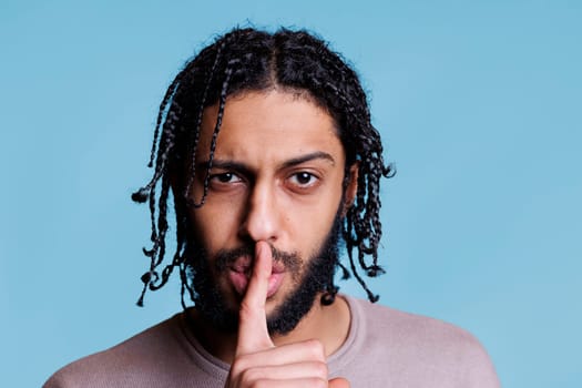 Arab man making silent gesture with serious facial expression
