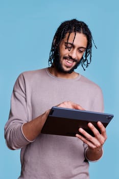 Smiling arab man typing online message on digital tablet