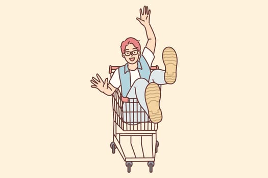 Cheerful man rides sitting in cart and supermarket after shopping and buying goods in store