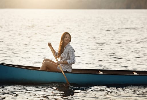 Sometimes this all I need. a beautiful young woman rowing a boat out on the lake.
