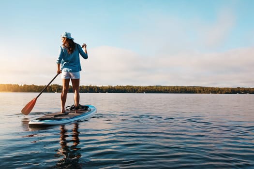 Theres so much you could do out here. a young woman paddle boarding on a lake.