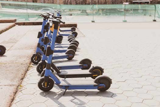 Row of electric scooters parked in city - Modern battery-powered rental vehicles for transport of people - Concept new trends of sustainable urban mobility