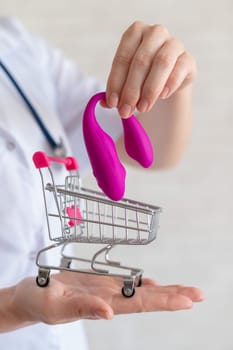 The faceless gynecologist recommends buying a clitoral vaginal vibrator to maintain women's health. The doctor holds a mini trolley and a masturbator for vivid orgasms.