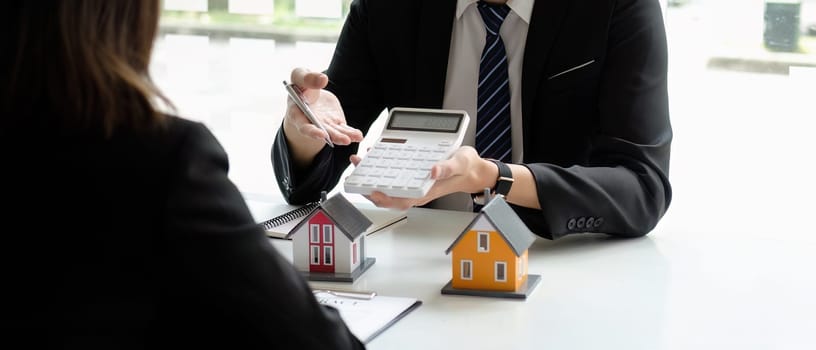 Real estate agents talk to client and offer good interest rates and calculate clients on mortgage financing to help them decide on real estate ideas with insurance