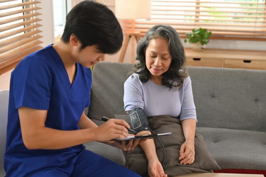 Asian male healthcare worker measuring blood pressure senior patient. Healthcare and home health care service