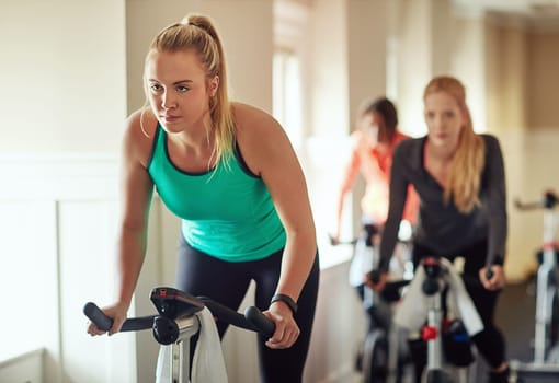 Blasting calories on a bike. a young woman working out with an exercise bike in a spinning class at the gym.