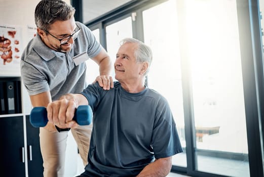 Youre doing a great job. a friendly physiotherapist helping his mature patient to use dumbbells in a rehabilitation center.