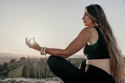 Fitness woman. Well looking middle aged woman with long hair, fitness instructor in leggings and tops doing stretching and pilates on the rock near forest. Female fitness yoga routine concept.