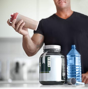 Man, hands and protein shake for nutrition, muscle gain or body mass product and supplement on kitchen table. Hand of male bodybuilder preparing pre workout drink for exercise or healthy meal at home