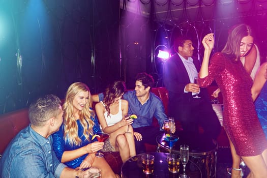 Why stay in when you can show up. a group of young adults enjoying themselves while out in a nightclub.