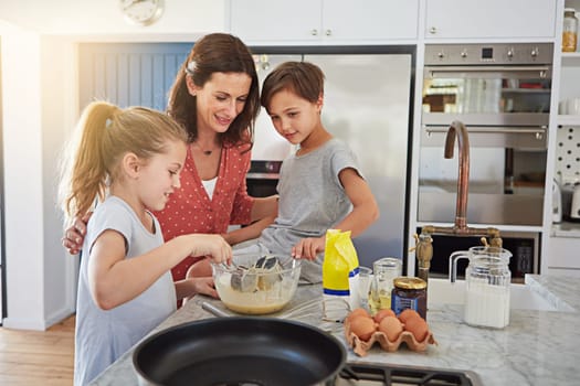 Showing them how to make their favorite treat. a single mother teaching her children how to make pancakes.
