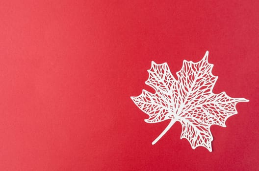The carve of white paper maple leaves on a red background.