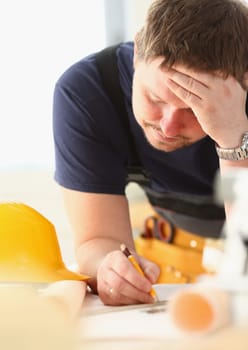 Pensive architect builder engineer thinks over blueprint