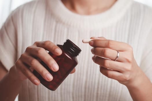 Asian woman's hand pouring medicines from a brown bottle