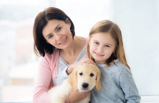 Sweet daughter and mother with lovely golden retriever dog