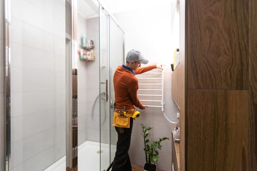Professional handyman working in shower booth indoors