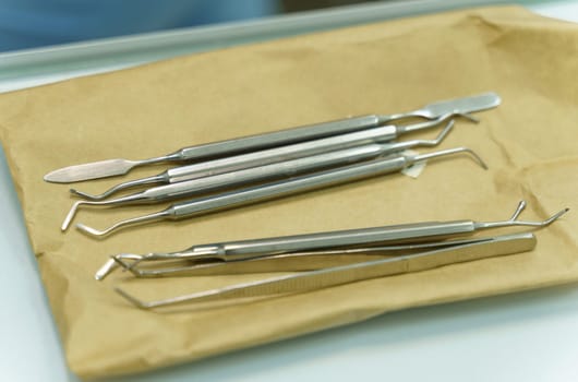 Dental instruments lie on wrapping paper before use. Close-up