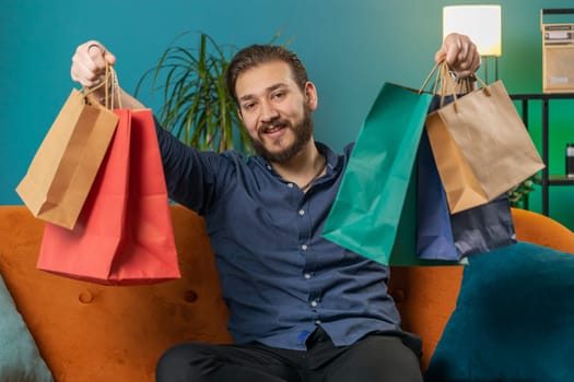 Happy lebanese man shopaholic consumer came back home after online shopping sale with bags at home