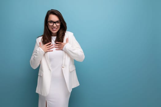 woman with thick dark hair in an office outfit on a blue studio background