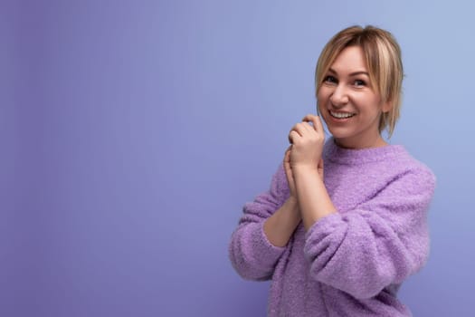 portrait of charming cute blondie woman in lavender sweater on purple background with copy space