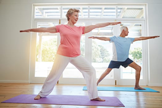 Yoga can add years to your life. Full length shot of a senior couple practicing yoga in their home.