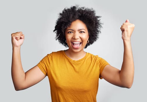 Portrait, winner and wow with a woman in studio on a gray background celebrating a victory or success. Motivation, smile and celebration with a happy young female model cheering her own achievement.