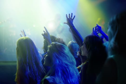 Crowd, neon lights and people at concert or music festival dancing with energy and hands up at night event. Dance, fun and group of excited fans in arena at rock band performance or audience at party