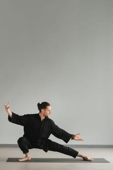 A man in black kimano practicing qigong energy exercises indoors