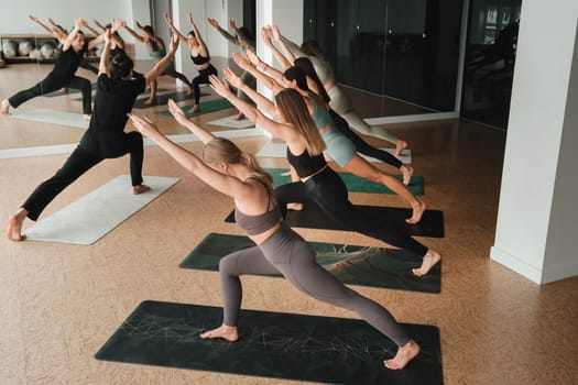 a group of girls do yoga in the gym under the guidance of a coach