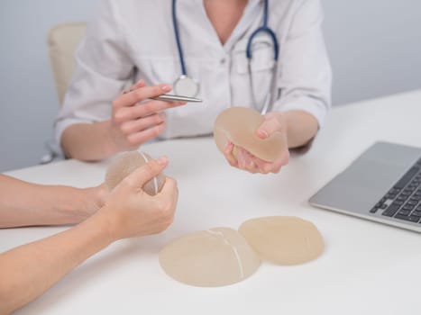 Caucasian woman and plastic surgeon touching and choosing breast implants.