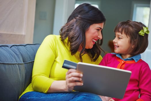 What app should Mommy buy for you. a mother and daughter using a credit card with a tablet at home.
