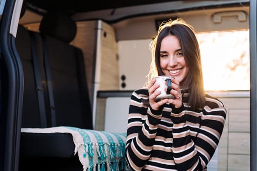 woman smiling in a camper van with a mug in hand