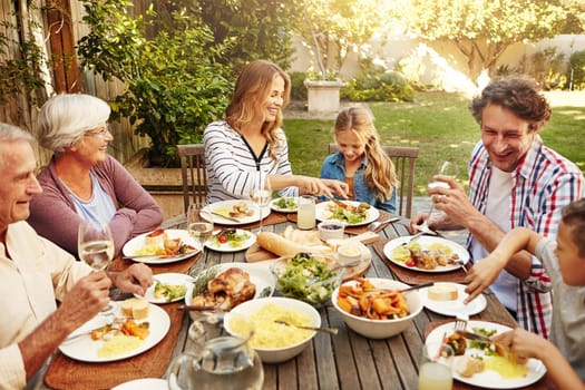Happiness is Sunday lunch with the family. a family eating lunch together outdoors.